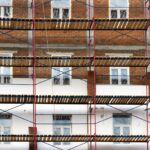 Façade en briques d'un immeuble collectif bruxellois entièrement recouverte d'un échafaudage pour un ravalement