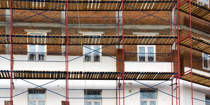 Façade en briques d'un immeuble collectif bruxellois entièrement recouverte d'un échafaudage pour un ravalement