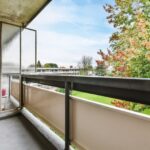 Balcon en béton d'un immeuble donnant sur un espace vert, exposé aux intempéries